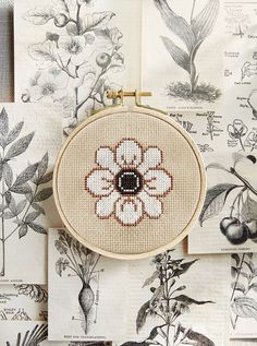 a cross stitched flower is hanging on a wall next to other drawings and pictures