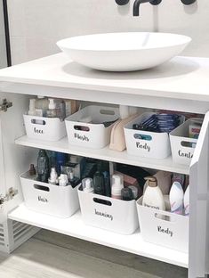 a white sink sitting on top of a bathroom vanity next to a counter with lots of containers