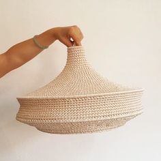 a person holding a woven basket in their right hand and the other hand is pointing at it