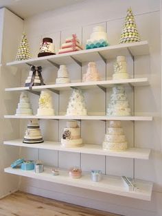 a shelf filled with lots of different types of cakes on top of white shelving