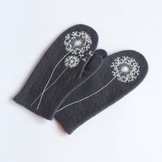 two black mittens with white dandelions on them sitting next to each other