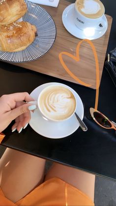 a woman sitting at a table with a cup of coffee and croissants