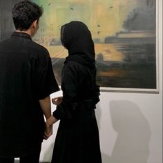 two people standing in front of a painting