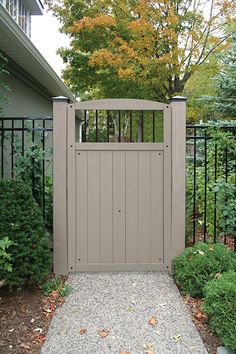 an open gate in the middle of a gravel path with trees and bushes behind it