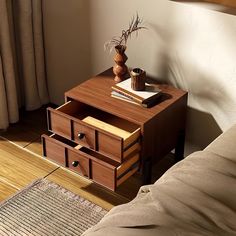 a wooden table with two drawers on top and a plant in the corner next to it