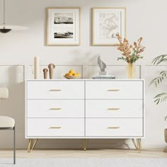 a white dresser sitting next to a chair and potted plant in a living room