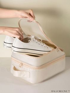 a pair of white tennis shoes sitting on top of an open shoe box with someone's hand