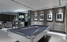 a pool table in the middle of a room with pictures on the wall behind it