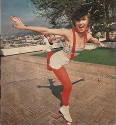 a woman in red and white is posing on a skateboard with her arms outstretched