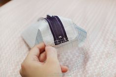 a person is holding something in their hand on top of a bed with pink and white bedspread