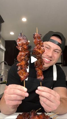 a man holding up two skewers of food