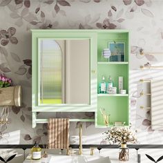 a bathroom with green cabinets and flowers on the wall