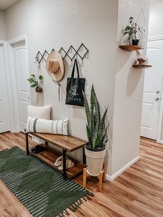 a living room filled with furniture and plants on top of a wooden floor next to a white wall