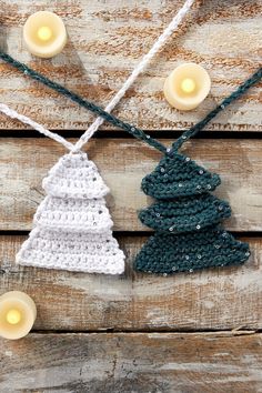 crocheted christmas tree ornament hanging from string on wooden table with candles