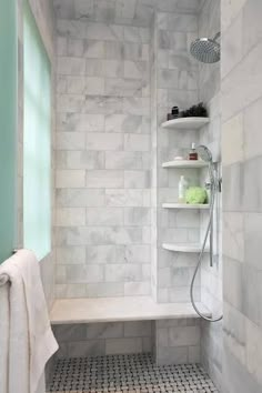 a bathroom with white marble walls and flooring, along with shelving units in the shower area