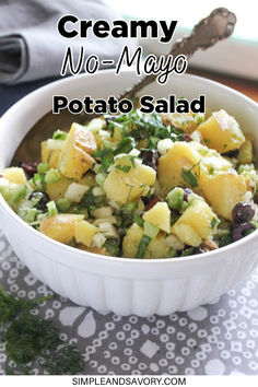 a white bowl filled with potato salad on top of a table next to a spoon