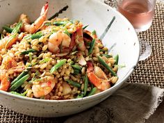 a white bowl filled with rice and shrimp on top of a table next to two glasses