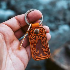 a hand holding a leather key chain with a bear design on the front and back