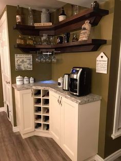 a kitchen with white cabinets and shelves filled with wine glasses, coffee maker and other items