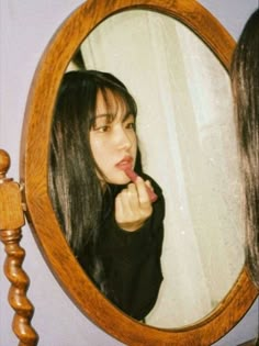 a young woman brushing her teeth in front of a mirror with the reflection of herself