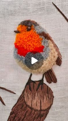 an embroidered bird sitting on top of a piece of cloth