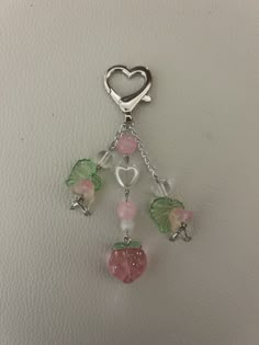 a key chain with charms attached to it on a white surface in the shape of a heart