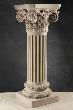 a white marble pedestal with an intricate design on top and two smaller columns in the middle