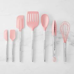 pink kitchen utensils lined up on a marble surface