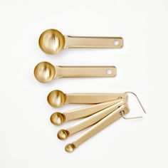 four golden measuring spoons and two metal scoops