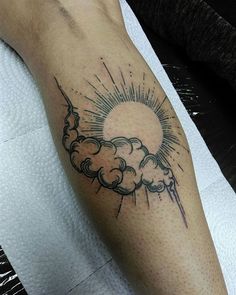 a person with a sun and clouds tattoo on their arm