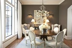 a dining room table with white chairs and chandelier