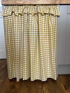 a kitchen with white and yellow checkered curtains hanging on the side of the counter