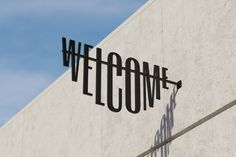 a welcome sign on the side of a building with blue sky in the back ground