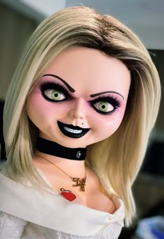 a creepy doll with long blonde hair and green eyes wearing a black choker around her neck