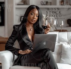 a woman sitting on a couch holding a glass of wine and looking at her laptop