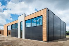 an industrial building with large windows and wood sidings on the outside, under a cloudy blue sky