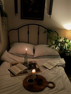 a lit candle sits on top of a bed with books and coffee mugs next to it