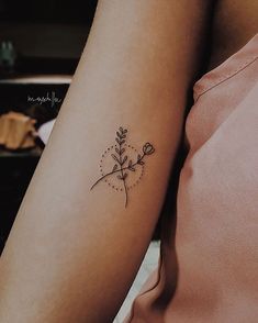 a woman's arm with a small flower tattoo on the left side of her arm