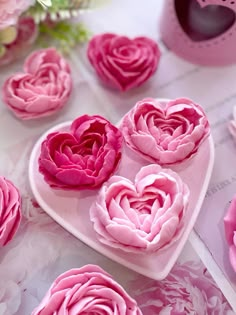 pink flowers are arranged on a heart shaped plate with other petals in the shape of hearts