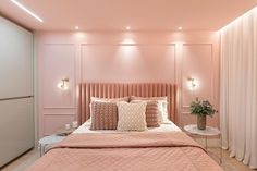 a bed with pink sheets and pillows in a room