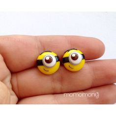 two small yellow and black earrings with eyes on each one's ear, in the palm of a hand