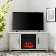 a flat screen tv sitting on top of a white entertainment center next to a fireplace