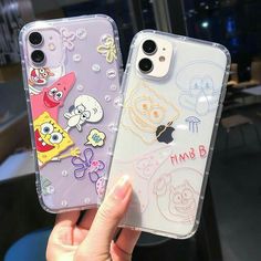 two cases with cartoon characters on them are held up by someone's hand in front of the camera