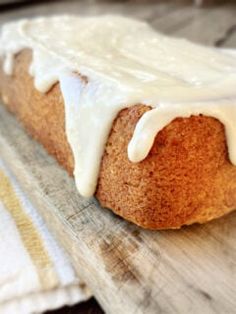 a loaf of bread with white icing sitting on top of a cutting board