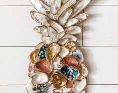 a metal pineapple with shells and seashells attached to the side of it