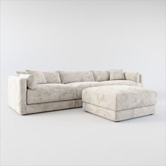 a large sectional couch sitting next to a footstool on top of a white floor