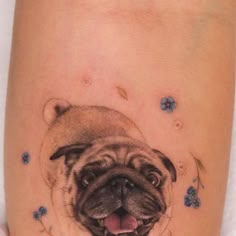 a small pug dog tattoo on the right side of the leg with blue flowers around it