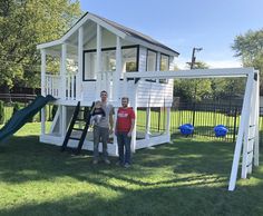 two people standing in front of a white play structure with a slide and climbing frame