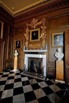 a room with a checkered floor, fireplace and pictures on the wall above it