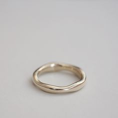 a gold wedding ring on a white surface with no one in the photo looking at it